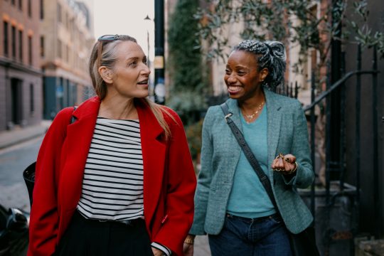 Mature friends walk down the street together with their luggage in hand looking for their vacation rental